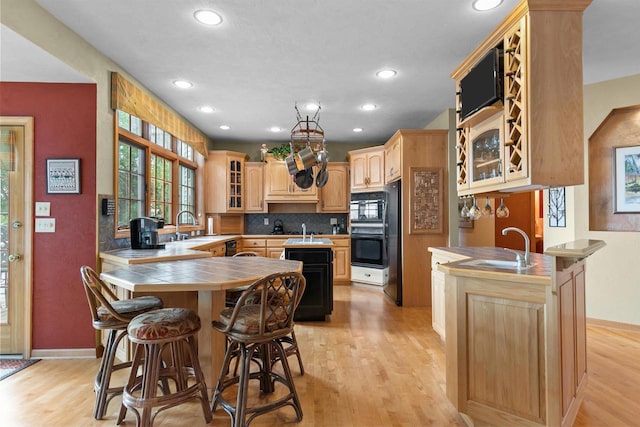 kitchen with tile counters, kitchen peninsula, sink, and light brown cabinetry