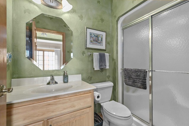 bathroom featuring vanity, toilet, and a shower with door