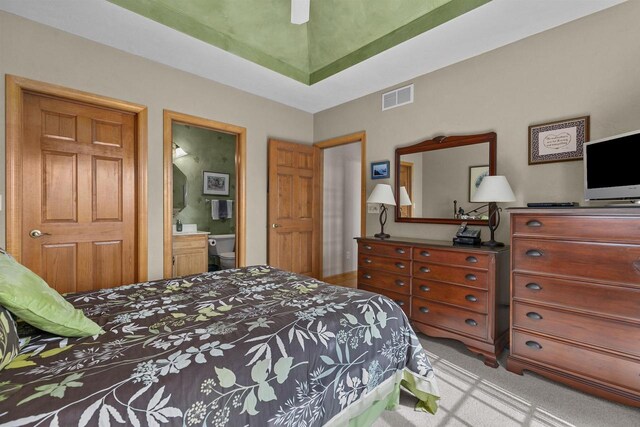 bedroom with ceiling fan, connected bathroom, and light carpet