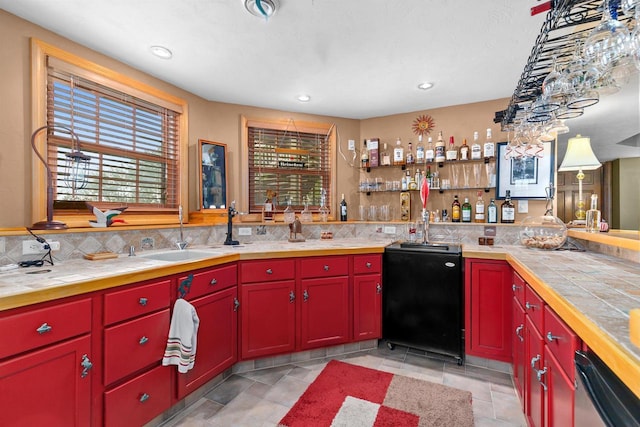 kitchen featuring sink, backsplash, tile counters, and dishwasher