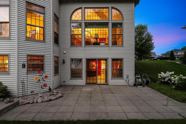 back house at dusk with a patio