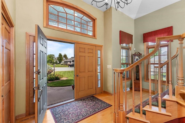 entryway with a towering ceiling, a chandelier, and light hardwood / wood-style flooring