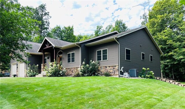 view of front of house featuring a front lawn, cooling unit, and a garage