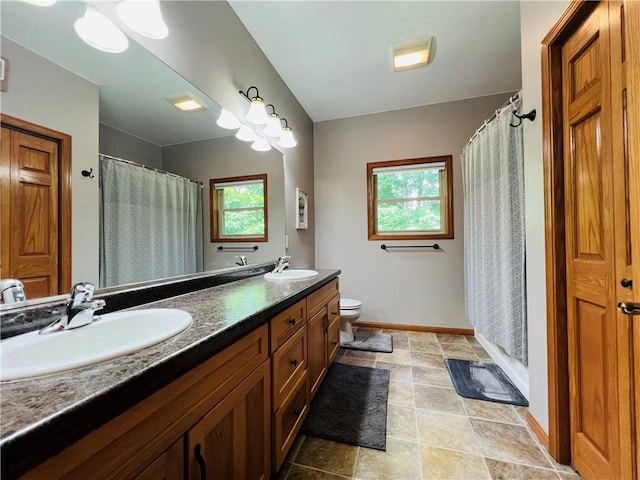 bathroom with walk in shower, plenty of natural light, toilet, and vanity