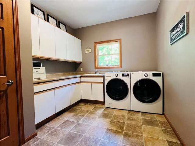 washroom with cabinets, washing machine and dryer, and sink