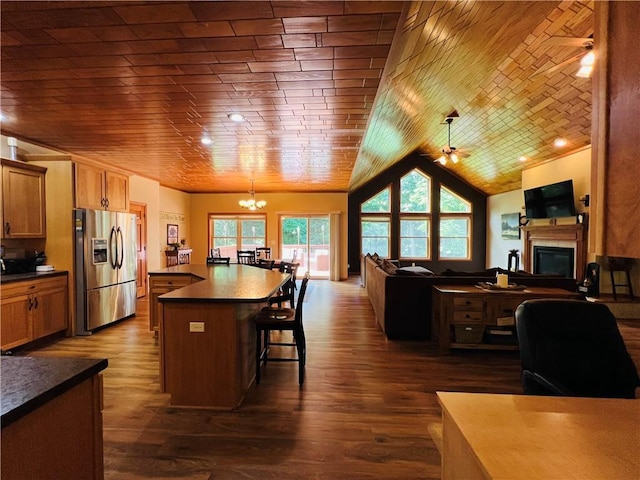 kitchen featuring pendant lighting, a kitchen breakfast bar, a center island, stainless steel refrigerator with ice dispenser, and ceiling fan with notable chandelier