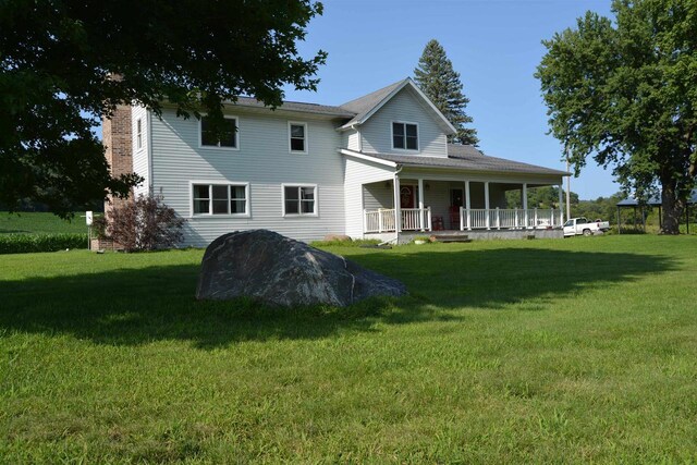 rear view of house featuring a lawn and a porch