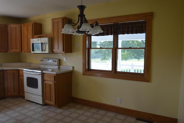 kitchen with an inviting chandelier, white appliances, baseboards, and brown cabinets