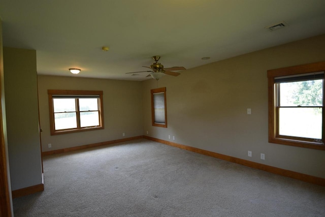 spare room with a wealth of natural light, visible vents, baseboards, and light colored carpet