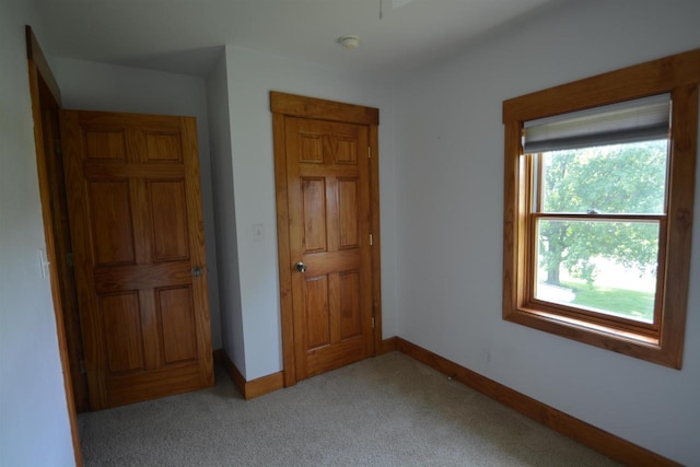 unfurnished bedroom with light colored carpet and baseboards