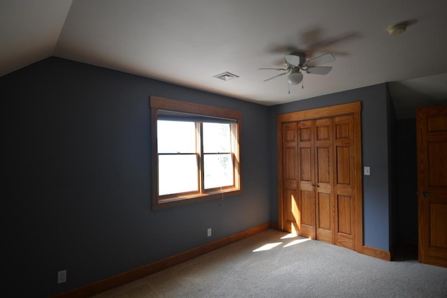 unfurnished bedroom featuring visible vents, a closet, carpet, baseboards, and vaulted ceiling