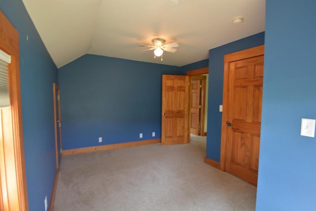 unfurnished bedroom featuring a ceiling fan, lofted ceiling, carpet, and baseboards