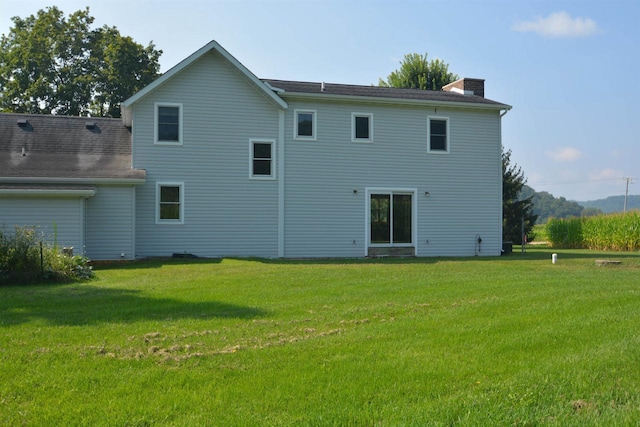 back of house featuring a chimney and a yard