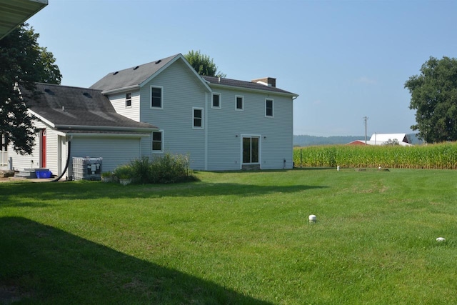 rear view of house with a chimney and a yard