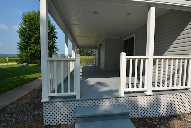 wooden terrace with a lawn and covered porch