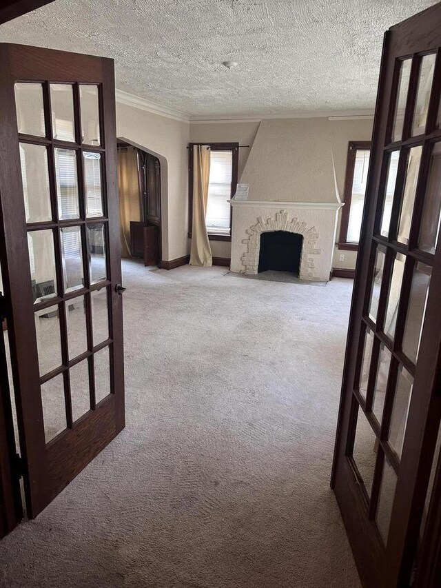 unfurnished living room featuring a fireplace, light carpet, and french doors