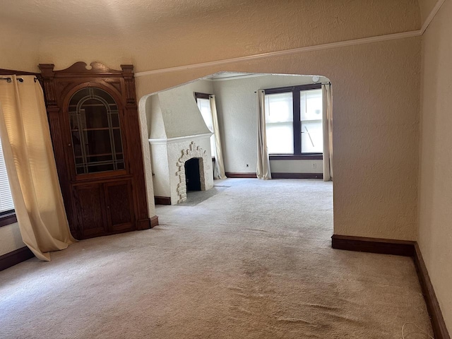 unfurnished living room featuring ornamental molding and light colored carpet