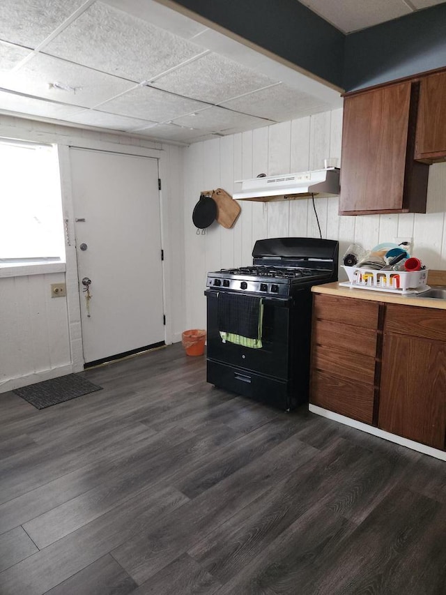 kitchen with dark hardwood / wood-style floors, a drop ceiling, and black gas range oven