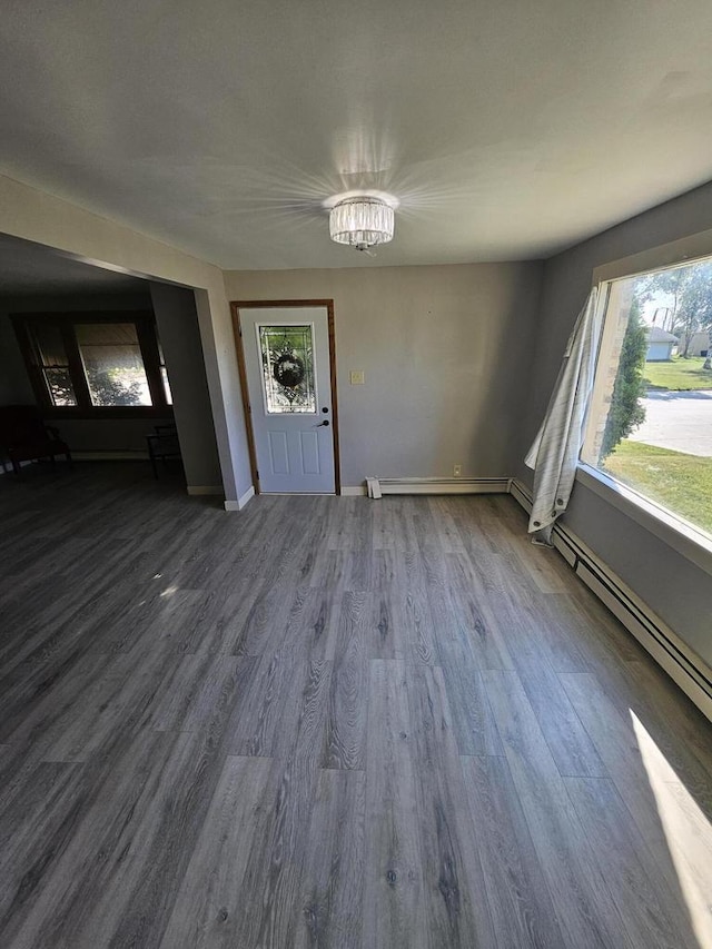 foyer with baseboard heating, a chandelier, plenty of natural light, and wood-type flooring