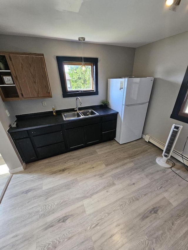 kitchen with white fridge, light hardwood / wood-style flooring, sink, hanging light fixtures, and dark brown cabinets