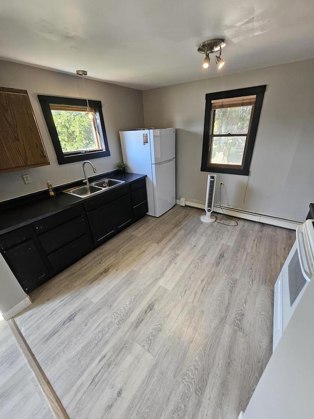 kitchen featuring light wood-type flooring, baseboard heating, pendant lighting, white refrigerator, and sink