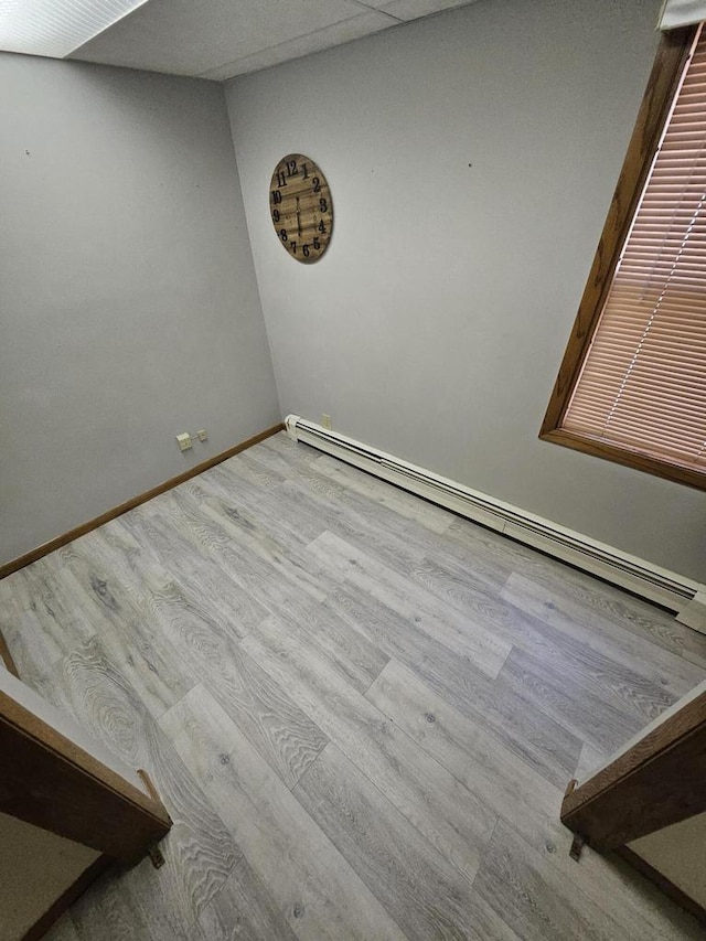 empty room with light hardwood / wood-style flooring and a baseboard heating unit