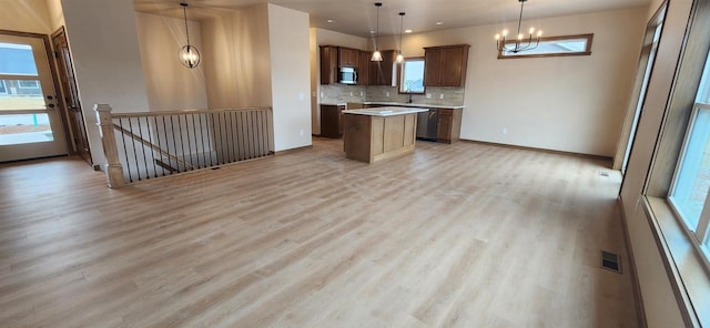 kitchen featuring an inviting chandelier, decorative light fixtures, appliances with stainless steel finishes, a kitchen island, and light hardwood / wood-style floors