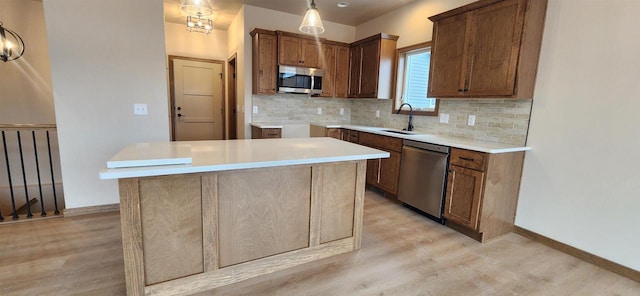 kitchen with a kitchen island, pendant lighting, sink, decorative backsplash, and stainless steel appliances