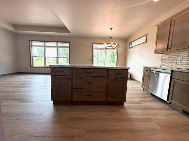 kitchen featuring stainless steel dishwasher, a healthy amount of sunlight, decorative light fixtures, and a raised ceiling