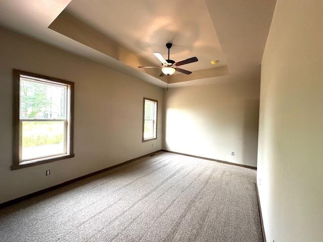 carpeted empty room featuring a tray ceiling and ceiling fan