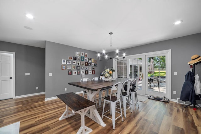 dining area with hardwood / wood-style flooring and an inviting chandelier