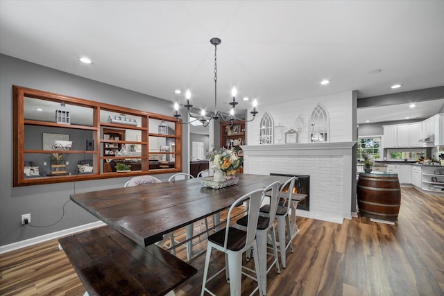 dining space featuring a fireplace, hardwood / wood-style floors, and an inviting chandelier