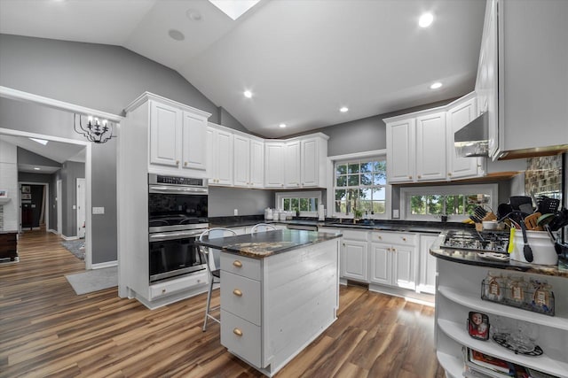 kitchen featuring a breakfast bar area, dark hardwood / wood-style flooring, stainless steel double oven, white cabinetry, and vaulted ceiling