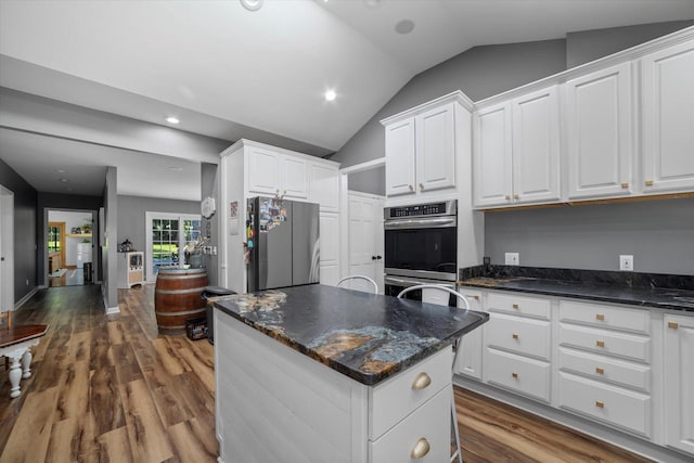 kitchen featuring appliances with stainless steel finishes, white cabinets, vaulted ceiling, a kitchen island, and wood-type flooring