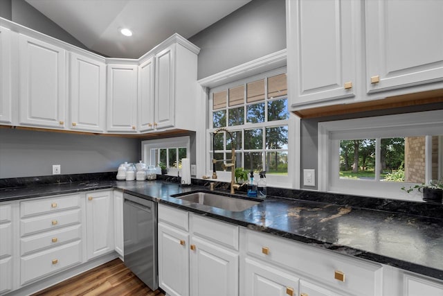 kitchen with stainless steel dishwasher, dark stone countertops, light wood-type flooring, and white cabinetry