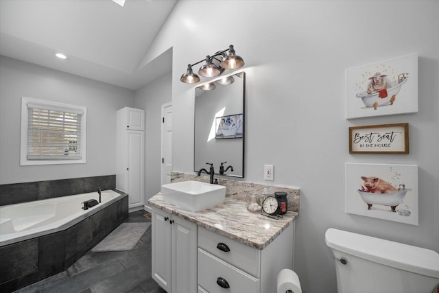 bathroom featuring toilet, tiled bath, lofted ceiling, tile patterned flooring, and vanity