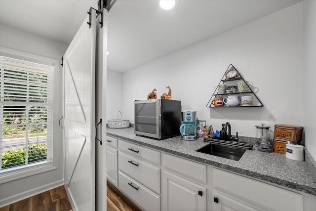 kitchen with a barn door, dark hardwood / wood-style floors, sink, and white cabinetry