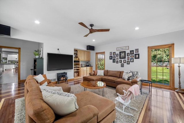 living room featuring a wood stove, hardwood / wood-style floors, and ceiling fan