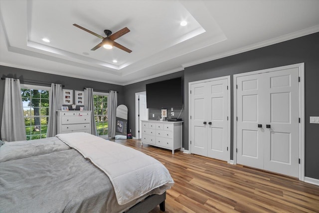 bedroom featuring ceiling fan, a raised ceiling, hardwood / wood-style floors, and crown molding