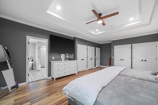 bedroom with ceiling fan, light tile patterned floors, two closets, and a tray ceiling