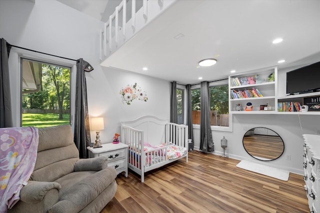 bedroom with a crib and hardwood / wood-style flooring