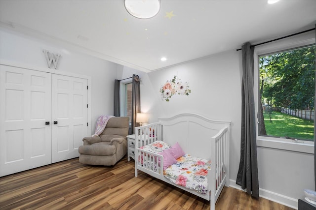 bedroom with wood-type flooring and a nursery area