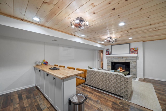 kitchen with wooden ceiling, dark wood-type flooring, a stone fireplace, and wood counters