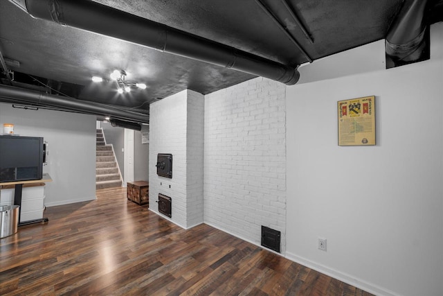 basement with hardwood / wood-style floors and brick wall