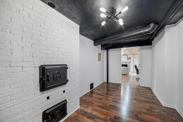 basement featuring brick wall, a fireplace, and dark hardwood / wood-style flooring