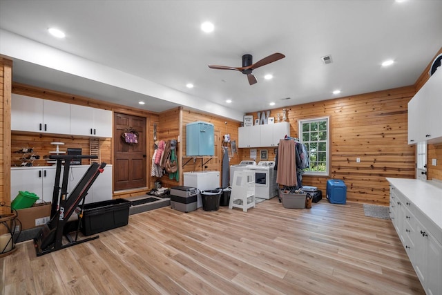 interior space with wooden walls, independent washer and dryer, ceiling fan, and light hardwood / wood-style floors