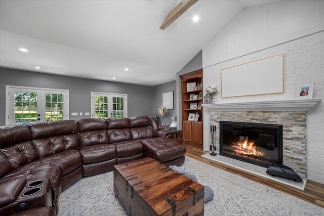 living room featuring vaulted ceiling with beams, a fireplace, french doors, and light hardwood / wood-style floors