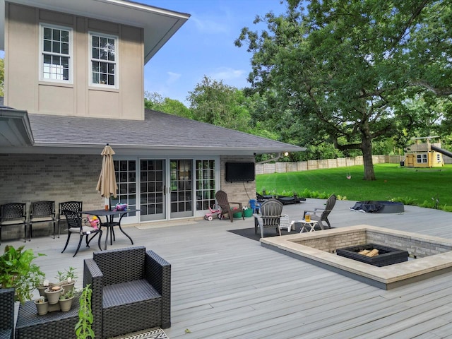 wooden deck with a yard and a fire pit