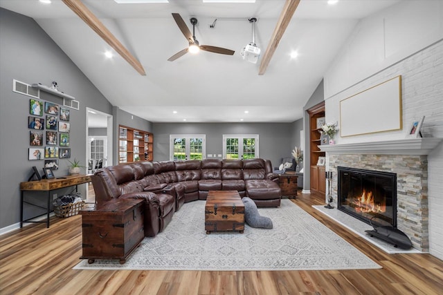 living room with ceiling fan, a fireplace, beam ceiling, and light hardwood / wood-style floors