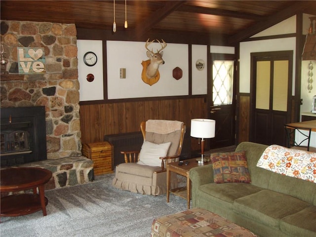 carpeted living room with wooden ceiling, beamed ceiling, a stone fireplace, and wainscoting